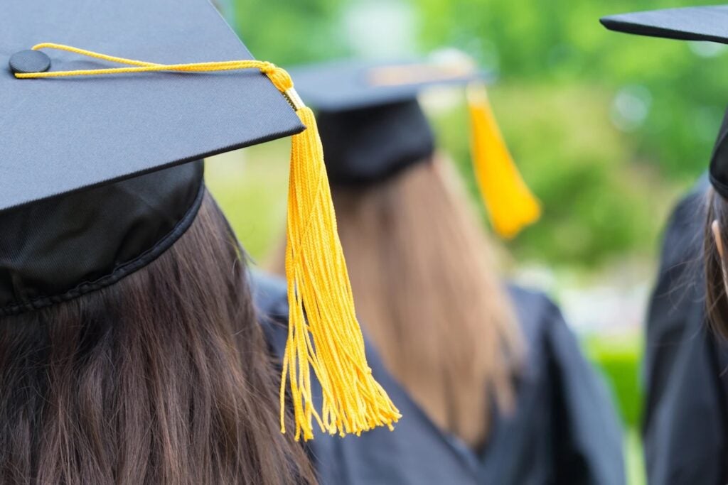 back of student's head with graduation cap and yellow tassel
