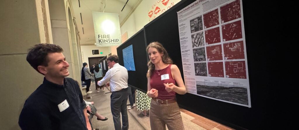 Two students stand in front of Urban Planning Applied Research PRoject poster in discussion
