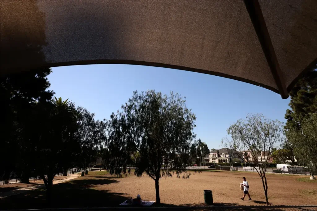 A man heads toward shade at the Hoover Recreation Center, where the playground is draped with a shade canopy.