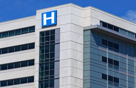large modern building with blue letter H sign for hospital