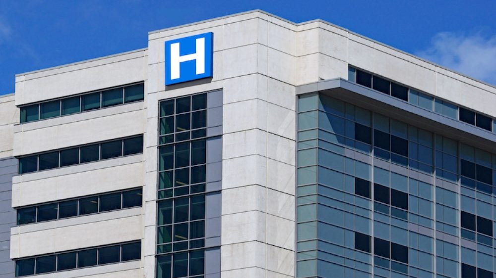 large modern building with blue letter H sign for hospital