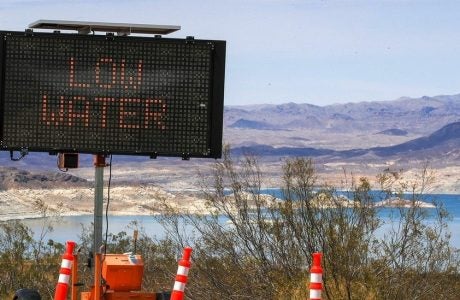 A road sign reads "Low Water" overlooking a lake.