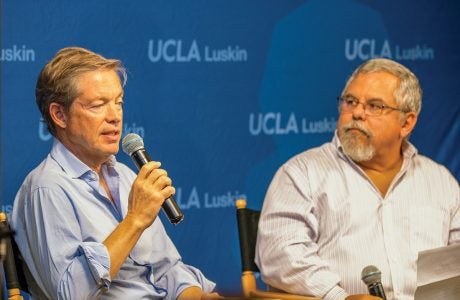 two men hold microphones as the talk