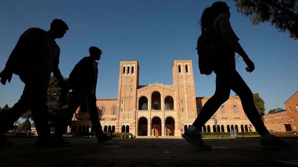 Silhouettes of students walk by in front of Royce Hall on UCLA campus.