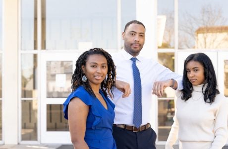Three students in front of glass entryway