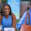 Woman wearing a blue tank top smiles at a friend at the Luskin Block Party