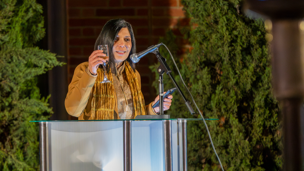 woman at podium raises champagne glass