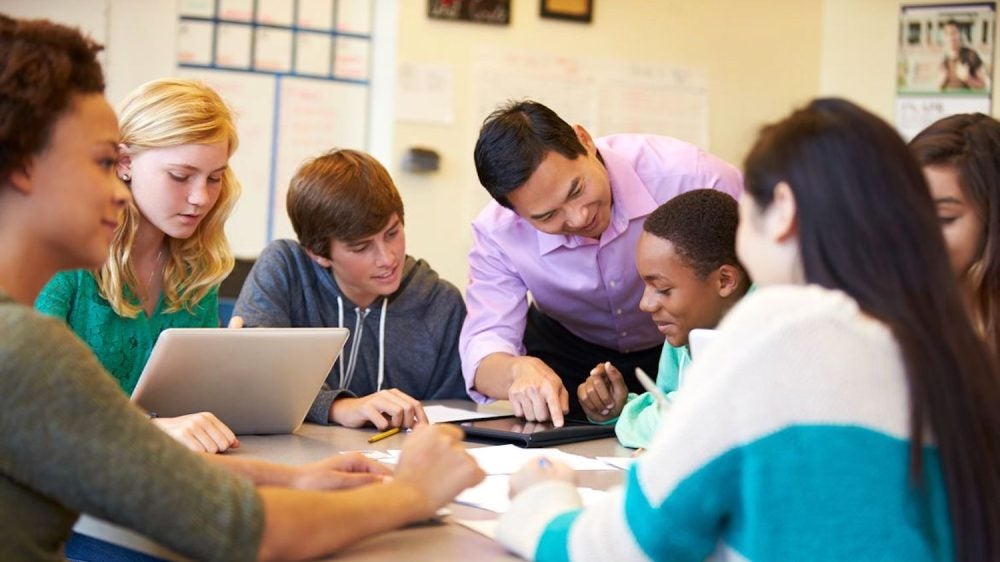 teacher with students sitting at table