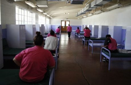 Incarcerated girls at the Camp Scott detention center in Santa Clarita sit on bunks facing away from the camera.