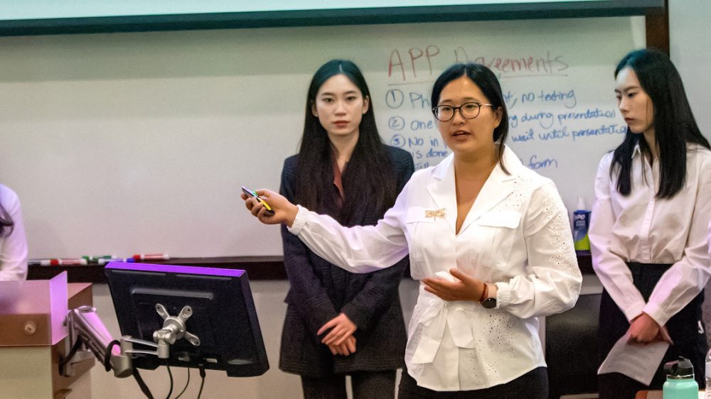 five young women in front of an erasable board in a classroom