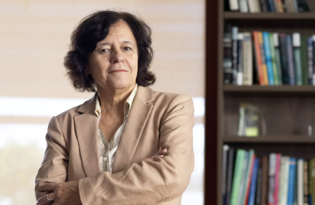 woman in tan suit next to bookcase