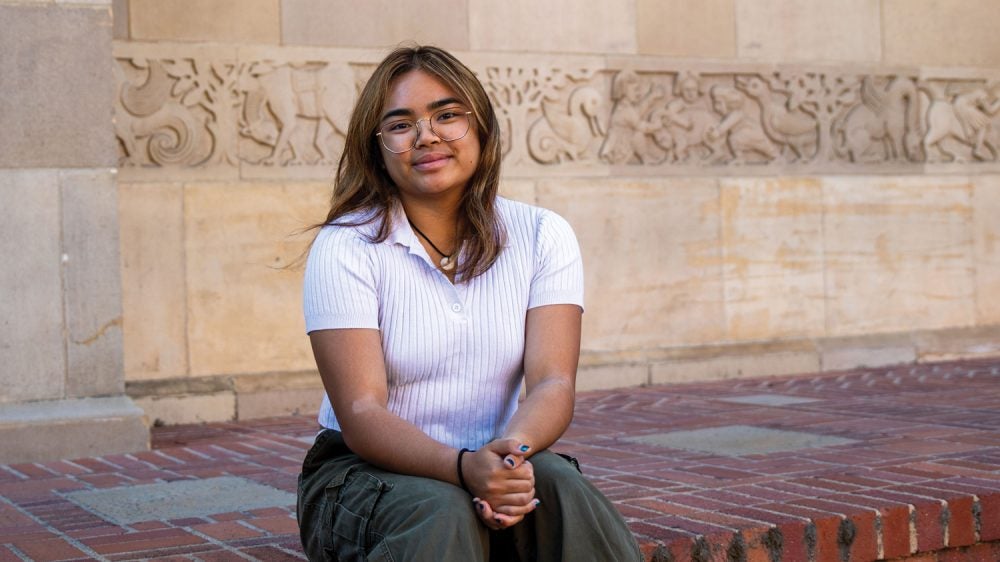 young woman sits on steps outside a building