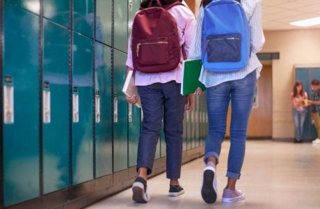 students with backpacks walking near school lockers