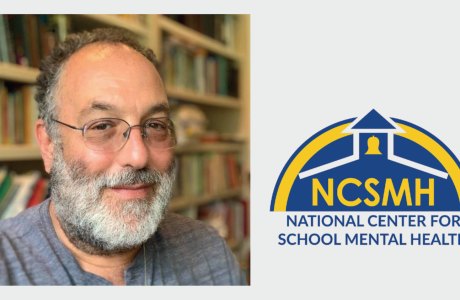 headshot of man with beard and glasses, with blue and yellow logo