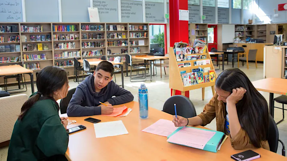 three students at table in school library