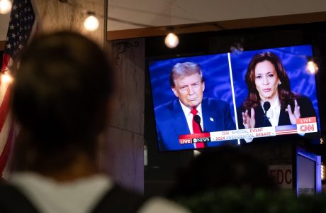 person watching television screen showing presidential candidates