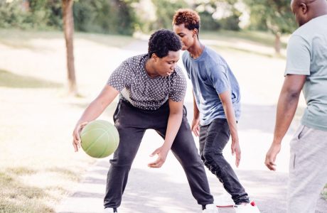 three boys are playing basketball|Young man sitting on the couch with a therapist.