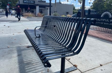 Bus stop steel bench with a metal armrest in the middle to deter people from laying down.