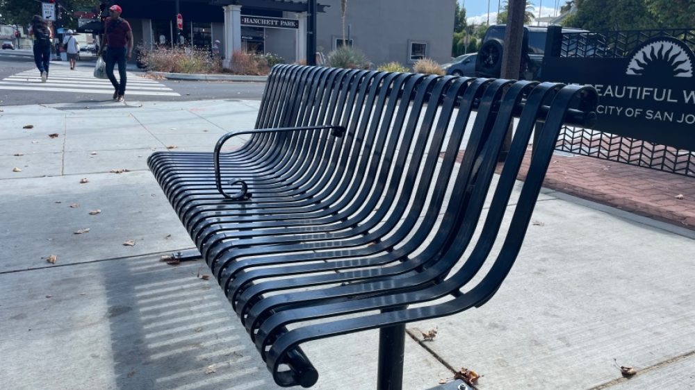 Bus stop steel bench with a metal armrest in the middle to deter people from laying down.