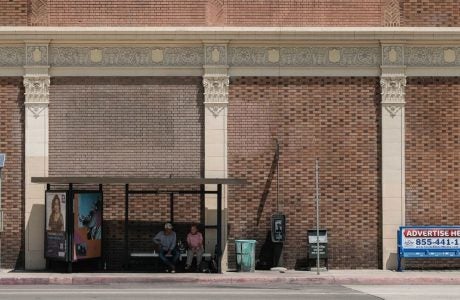 Two people sitting at bus shelter