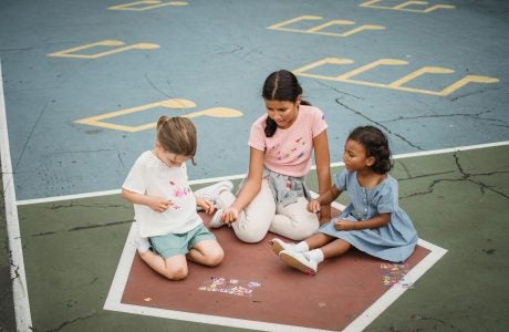Three young school girls play on the floor during recess||