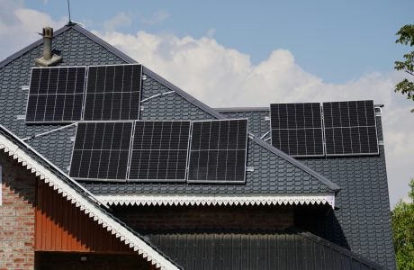 photo of a rooftop of a home with lots of solar panels on it.|Buildings in a city.|a worker on the roof of a home installing solar panels||