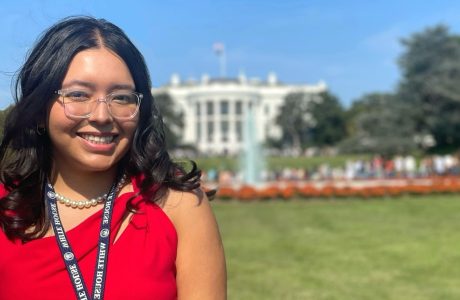 woman in red top in front of White House