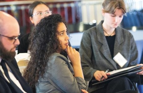 young woman with curly dark hair listens to speaker|