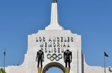 top of white building with spire and Olympic Games logo