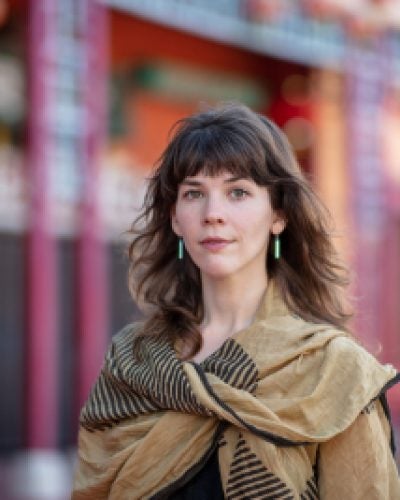 person standing outdoors wearing large scarf