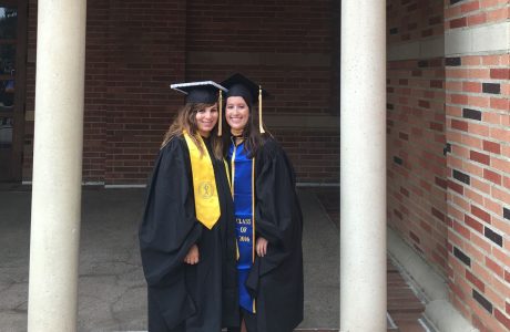 MSW Alumni Emily Dillon graduate of 2016 class, stands with her female friend, both are in cap and gown at UCLA graduation in front of a brick building.||