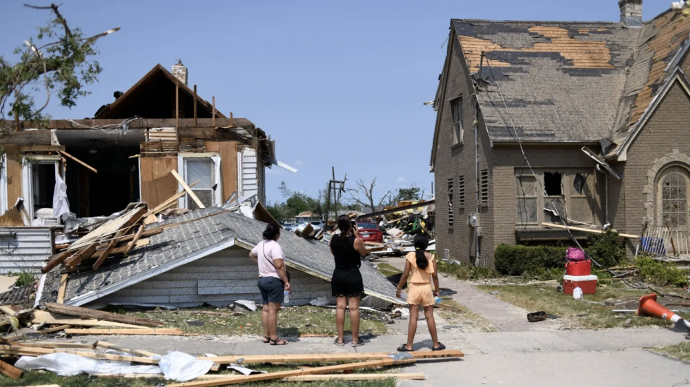 residents in front of damaged home with roof ripped off
