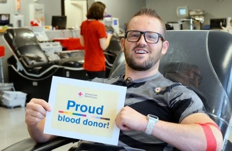 man in glasses with sign that says Proud blood donor