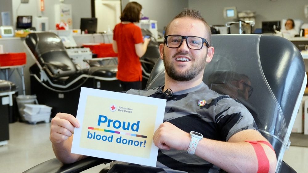 man in glasses with sign that says Proud blood donor