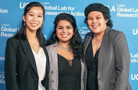three young people smile in front of UCLA backdrop