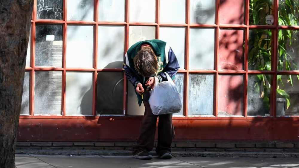 a person holding a shopping bag slumps forward in front of a multipane window