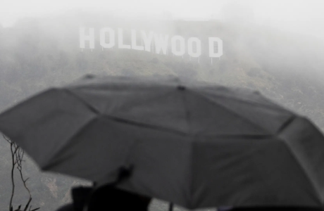 People with umbrella at Hollywood sign during storm