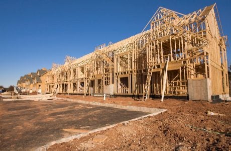 a complex of buildines in process of getting built, framing is done and some sheathing sitting on a muddy construction site.