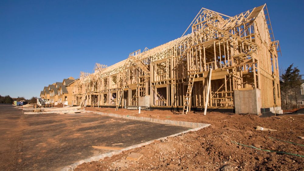 a complex of buildines in process of getting built, framing is done and some sheathing sitting on a muddy construction site.