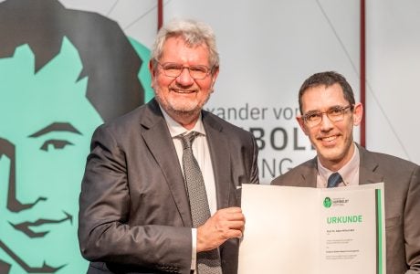 Two men holding paper folder holding award statement