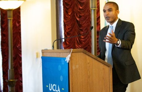man in suit and tie gestures with one hand from podium