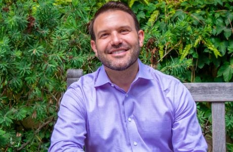 man in purple shirt sitting on outdoor bench