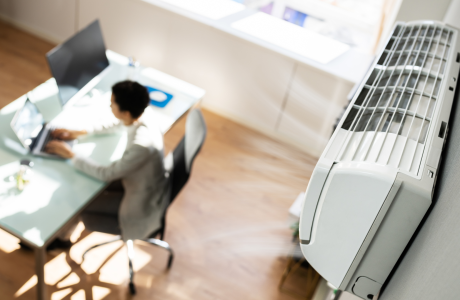 A person working at a desk with a wall mount air conditioner in the frame/