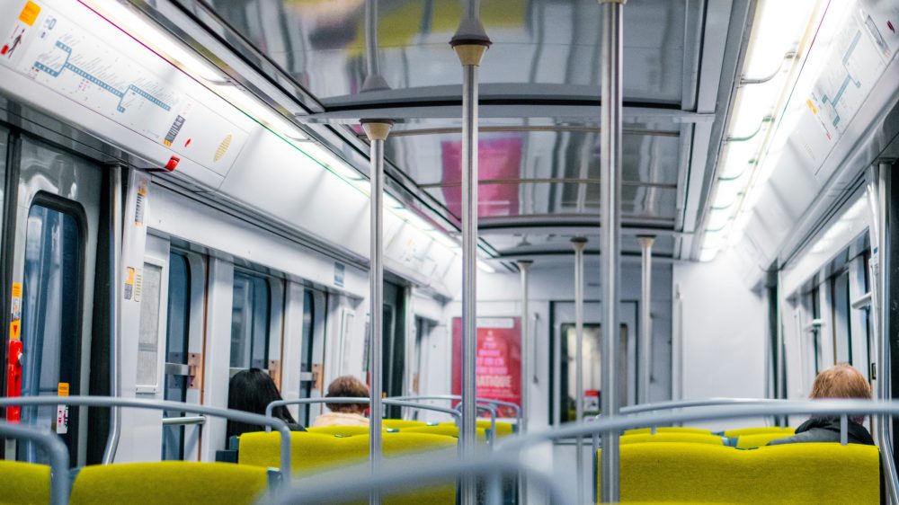 Interior shot of a Paris public transit train with some passengers seated.
