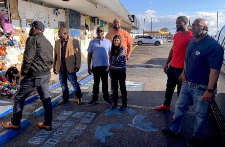 woman and men in front of memorial in parking lot