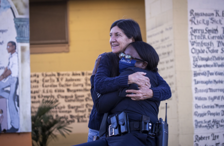 image shows professor Jorja Leap hugging a police officer|stock art shows people in shadow on a city street