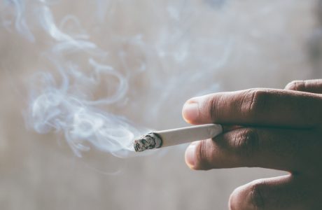 Hand holding lit cigarette and showing smoke