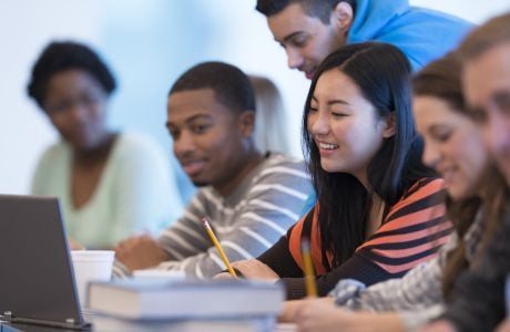 Young people at a desk with books and laptop