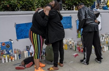 people mourn near sidewalk memorial for slain youth