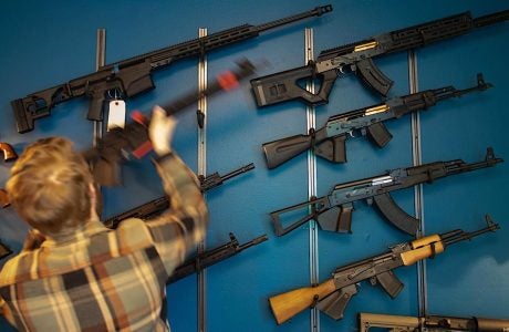 man facing wall lined with firearms for sale